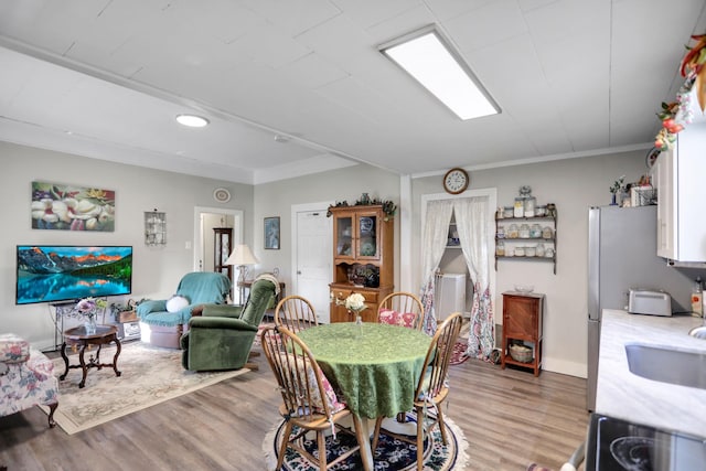 dining area with light hardwood / wood-style flooring and ornamental molding