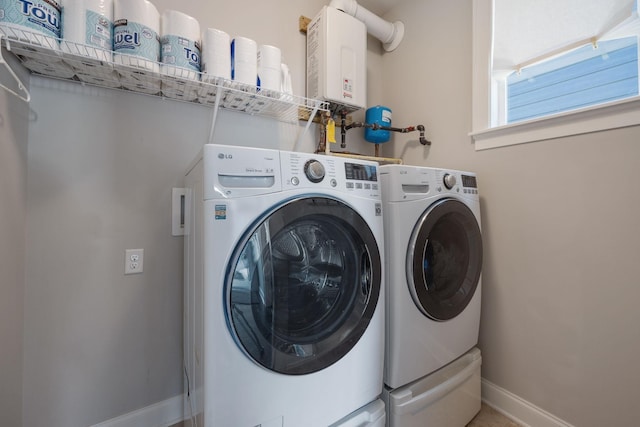 laundry area with tankless water heater, laundry area, washing machine and clothes dryer, and baseboards