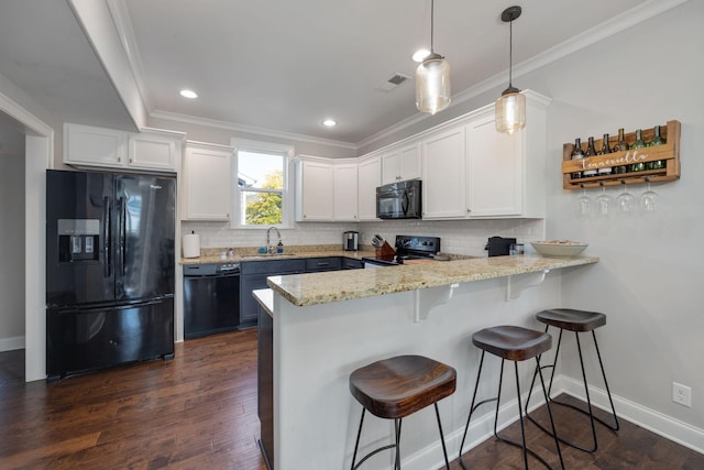 kitchen with a breakfast bar, a sink, white cabinetry, black appliances, and pendant lighting