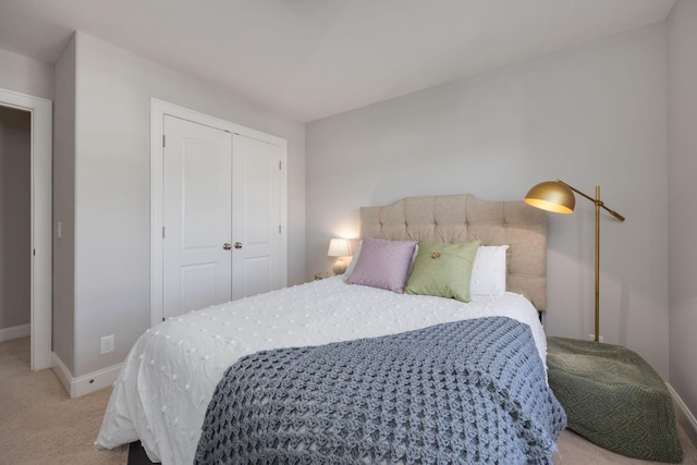 bedroom featuring baseboards, a closet, and light colored carpet