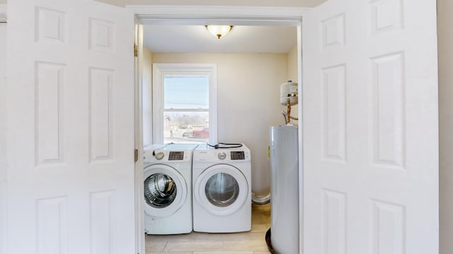 clothes washing area with light hardwood / wood-style flooring, gas water heater, and washer and clothes dryer