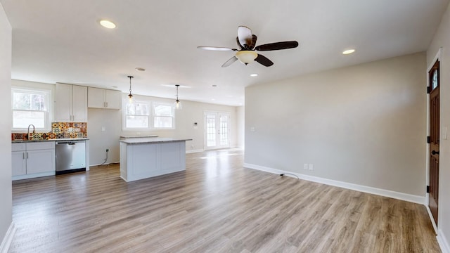 kitchen featuring sink, decorative light fixtures, a center island, dishwasher, and light hardwood / wood-style floors