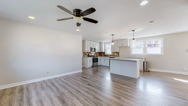 kitchen with white cabinetry, hanging light fixtures, stainless steel appliances, and a kitchen island