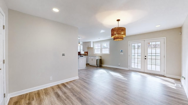 unfurnished living room featuring french doors and light wood-type flooring