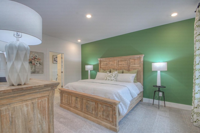 bedroom with ensuite bathroom and light colored carpet