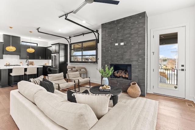 living room featuring plenty of natural light, a large fireplace, sink, and light hardwood / wood-style flooring