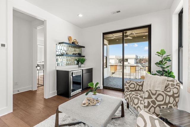 living room featuring hardwood / wood-style flooring, beverage cooler, and bar area