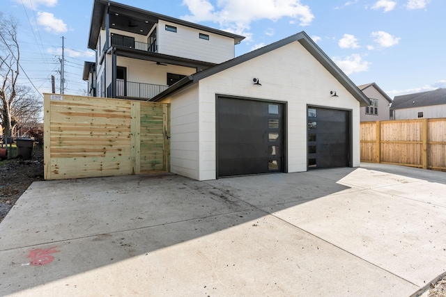 rear view of property featuring a garage, a balcony, and an outdoor structure