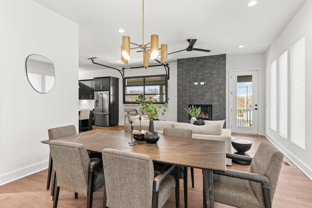 dining area featuring an inviting chandelier, a fireplace, and wood-type flooring