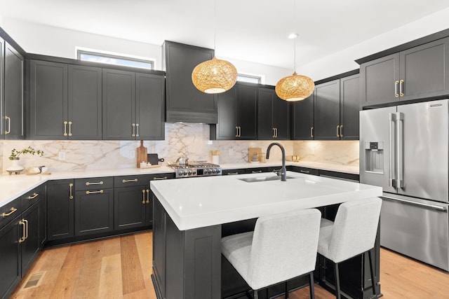 kitchen featuring pendant lighting, sink, a breakfast bar area, high end fridge, and a center island with sink