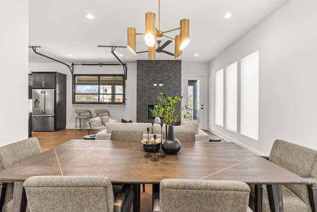 dining space with hardwood / wood-style flooring, an inviting chandelier, and a fireplace