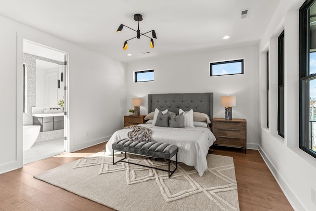 bedroom featuring hardwood / wood-style flooring, ensuite bath, and multiple windows