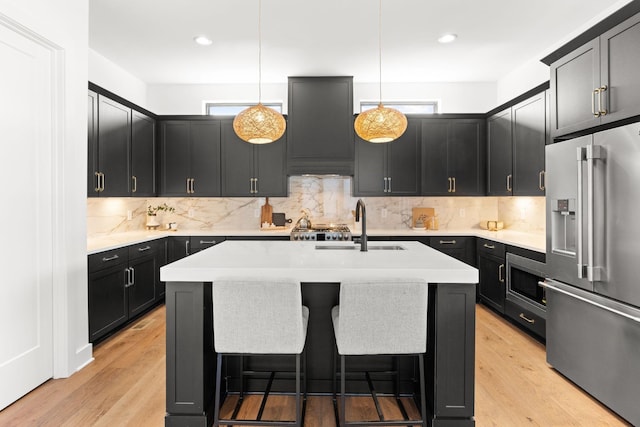 kitchen with decorative light fixtures, a breakfast bar area, stainless steel appliances, and an island with sink