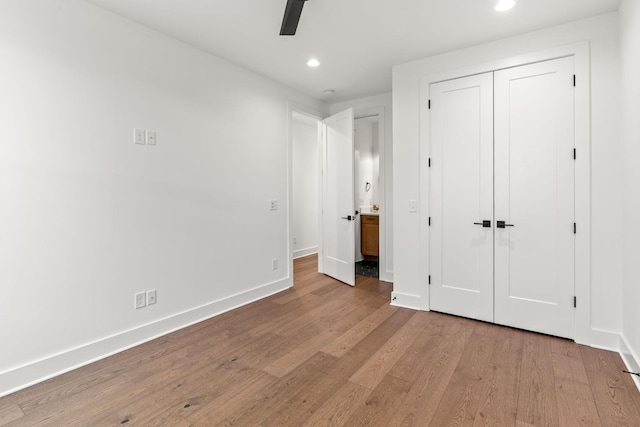 unfurnished bedroom featuring ceiling fan, a closet, and light wood-type flooring