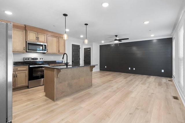 kitchen with sink, appliances with stainless steel finishes, hanging light fixtures, a kitchen breakfast bar, and an island with sink