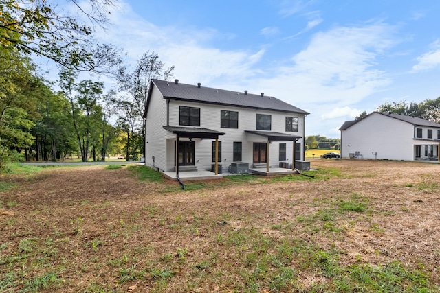 back of property with a yard, central air condition unit, and a patio area