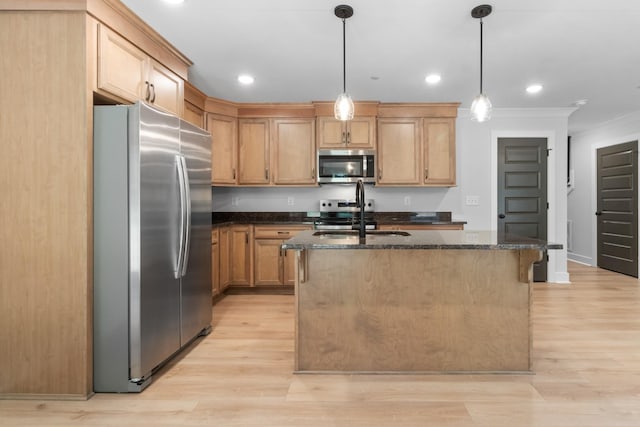 kitchen with appliances with stainless steel finishes, hanging light fixtures, sink, and a center island with sink