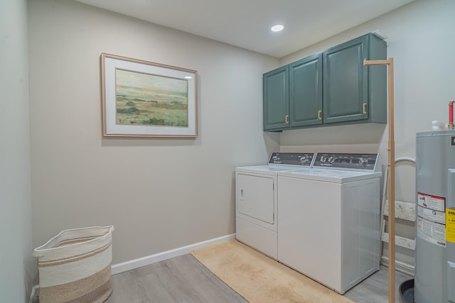 washroom with electric water heater, light hardwood / wood-style flooring, washing machine and dryer, and cabinets