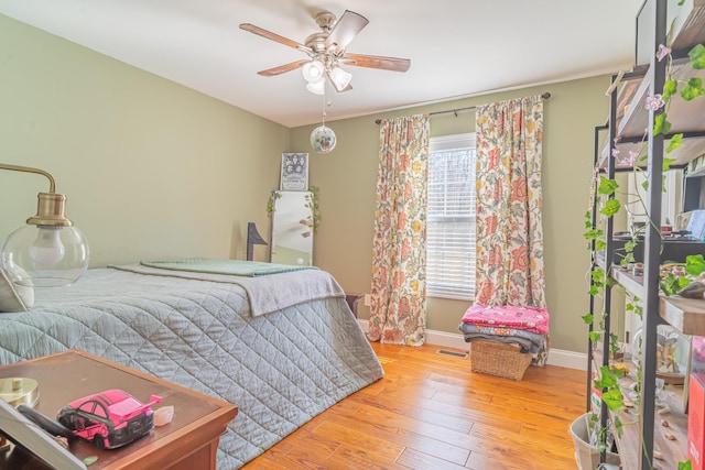 bedroom featuring multiple windows, hardwood / wood-style flooring, and ceiling fan