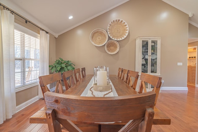 dining room with vaulted ceiling, ornamental molding, and light hardwood / wood-style floors