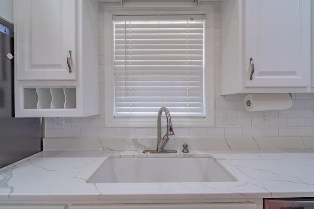 kitchen with white cabinetry, light stone countertops, sink, and backsplash