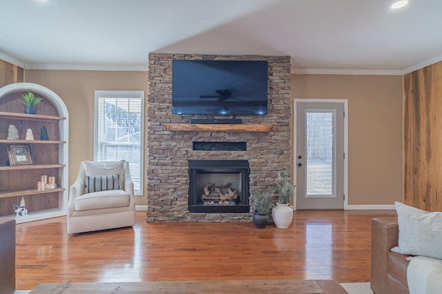 living room featuring crown molding, light wood-type flooring, and a fireplace