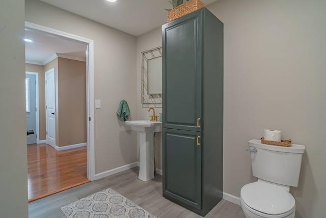 bathroom with crown molding, sink, hardwood / wood-style floors, and toilet