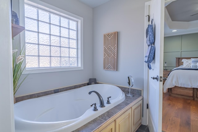 bathroom with hardwood / wood-style flooring, a healthy amount of sunlight, and a bath