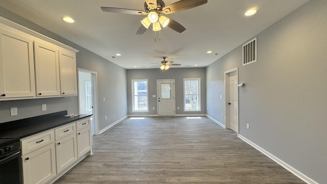 kitchen with stove, hardwood / wood-style floors, and white cabinets