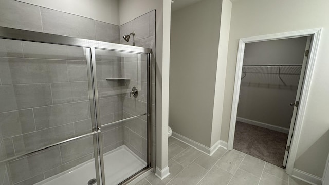 bathroom featuring toilet, an enclosed shower, and tile patterned flooring