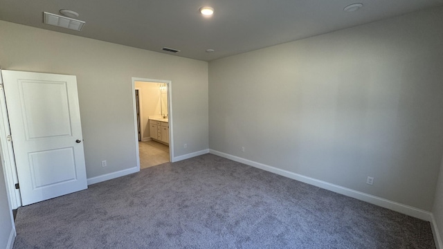 unfurnished bedroom featuring light colored carpet and ensuite bathroom