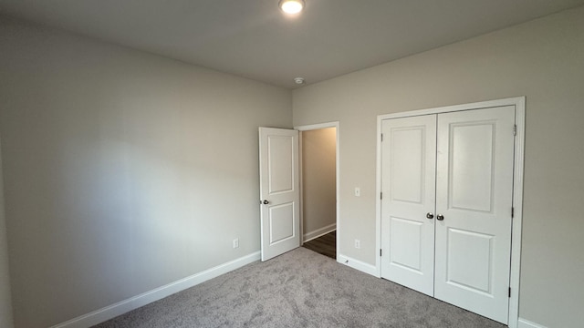 unfurnished bedroom featuring light colored carpet and a closet