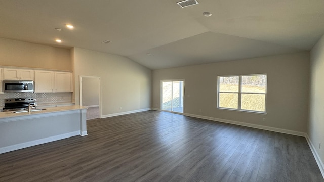 kitchen featuring dark hardwood / wood-style floors, lofted ceiling, white cabinets, backsplash, and stainless steel appliances