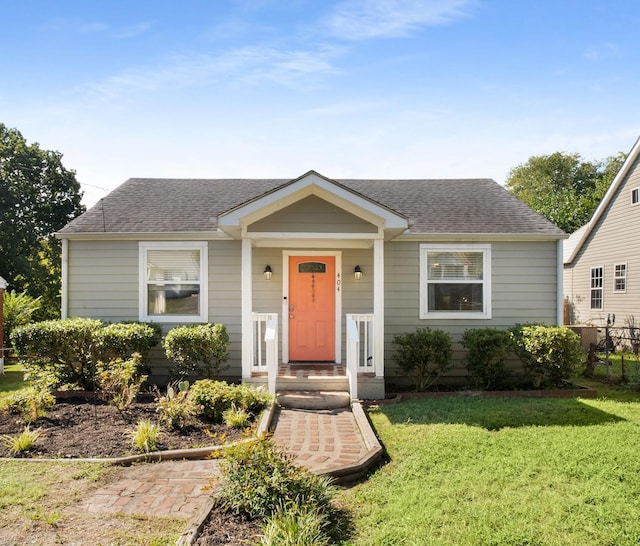 bungalow-style home featuring a front lawn and roof with shingles