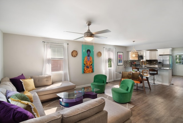 living area with a ceiling fan, wood finished floors, and baseboards