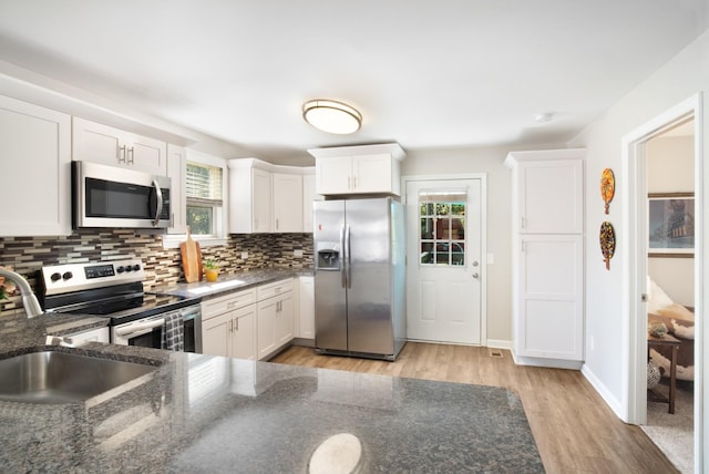 kitchen with white cabinetry, decorative backsplash, light hardwood / wood-style flooring, and stainless steel appliances