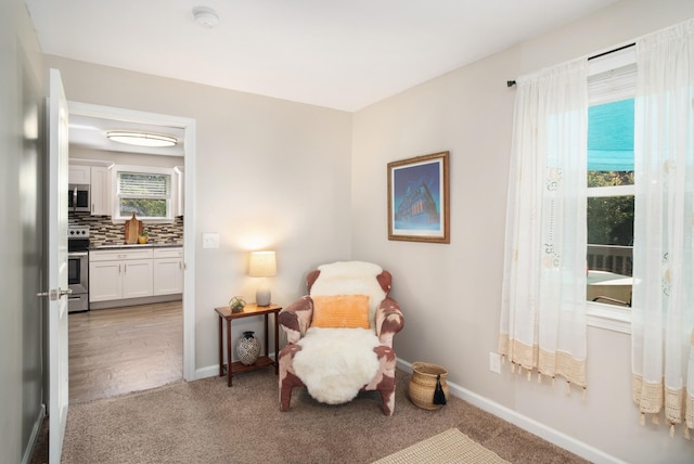 sitting room with baseboards and light carpet