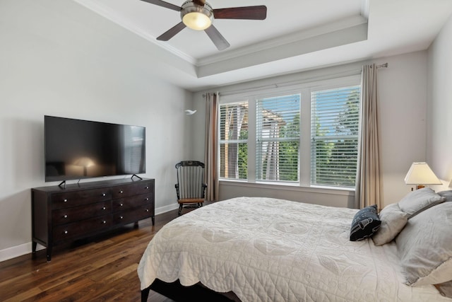 bedroom featuring ornamental molding, dark hardwood / wood-style floors, ceiling fan, and a tray ceiling