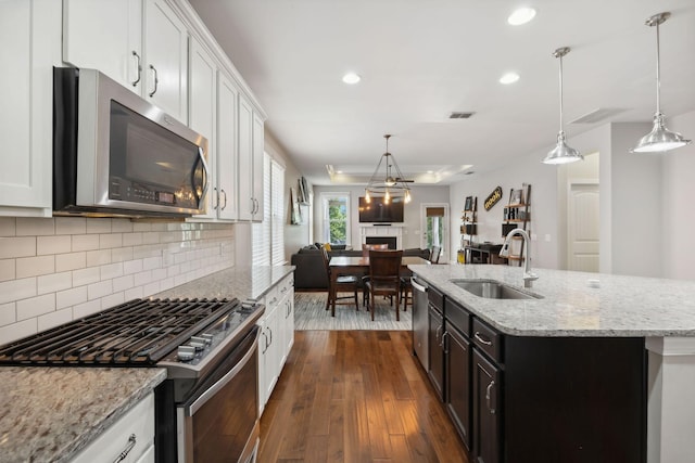 kitchen with an island with sink, stainless steel appliances, sink, and white cabinets