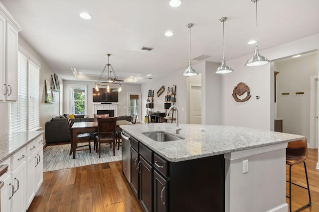 kitchen featuring white cabinetry, an island with sink, sink, and pendant lighting