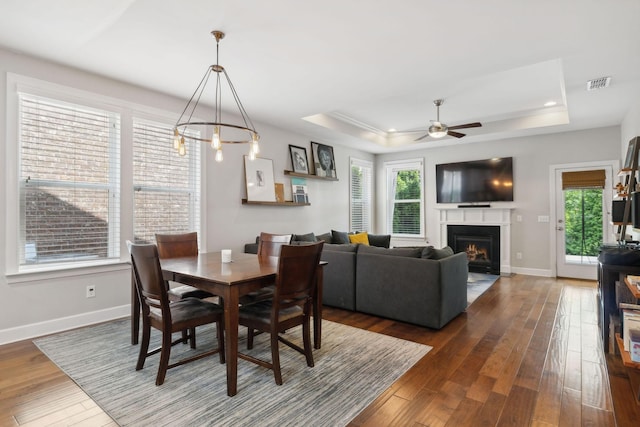 dining area with dark wood-type flooring, ceiling fan, and a tray ceiling