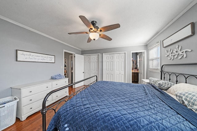 bedroom with ensuite bath, ceiling fan, a textured ceiling, dark hardwood / wood-style flooring, and two closets