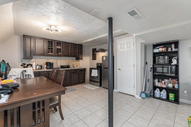 kitchen with light tile patterned floors, dark brown cabinets, a textured ceiling, and appliances with stainless steel finishes