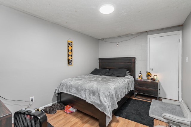 bedroom featuring hardwood / wood-style flooring, a large fireplace, and a textured ceiling