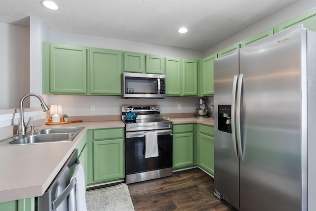 kitchen featuring appliances with stainless steel finishes, sink, dark hardwood / wood-style flooring, green cabinets, and a textured ceiling