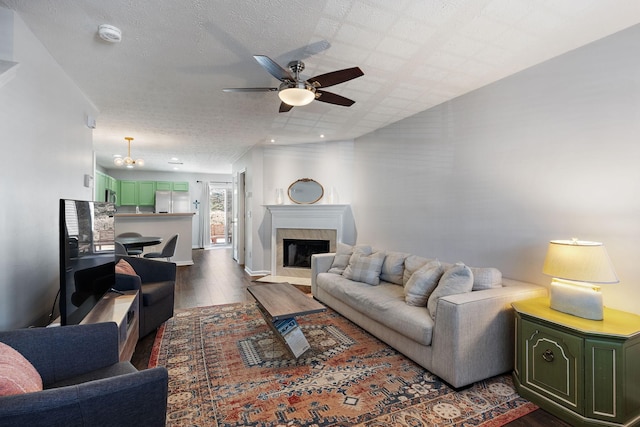 living room with dark wood-type flooring, ceiling fan, and a textured ceiling