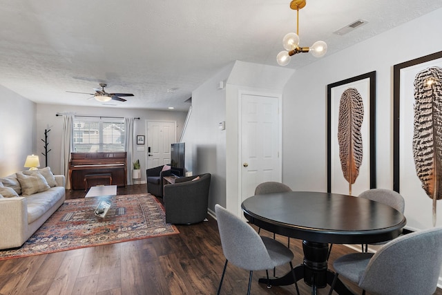 dining space featuring dark hardwood / wood-style flooring, ceiling fan with notable chandelier, and a textured ceiling