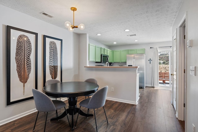 dining space featuring dark hardwood / wood-style flooring, a textured ceiling, and a notable chandelier