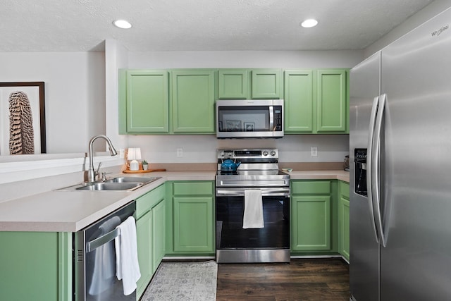 kitchen featuring sink, green cabinetry, a textured ceiling, appliances with stainless steel finishes, and dark hardwood / wood-style flooring