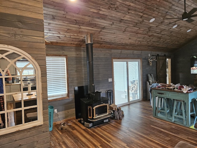 living room featuring wooden walls, lofted ceiling, a barn door, and a wealth of natural light